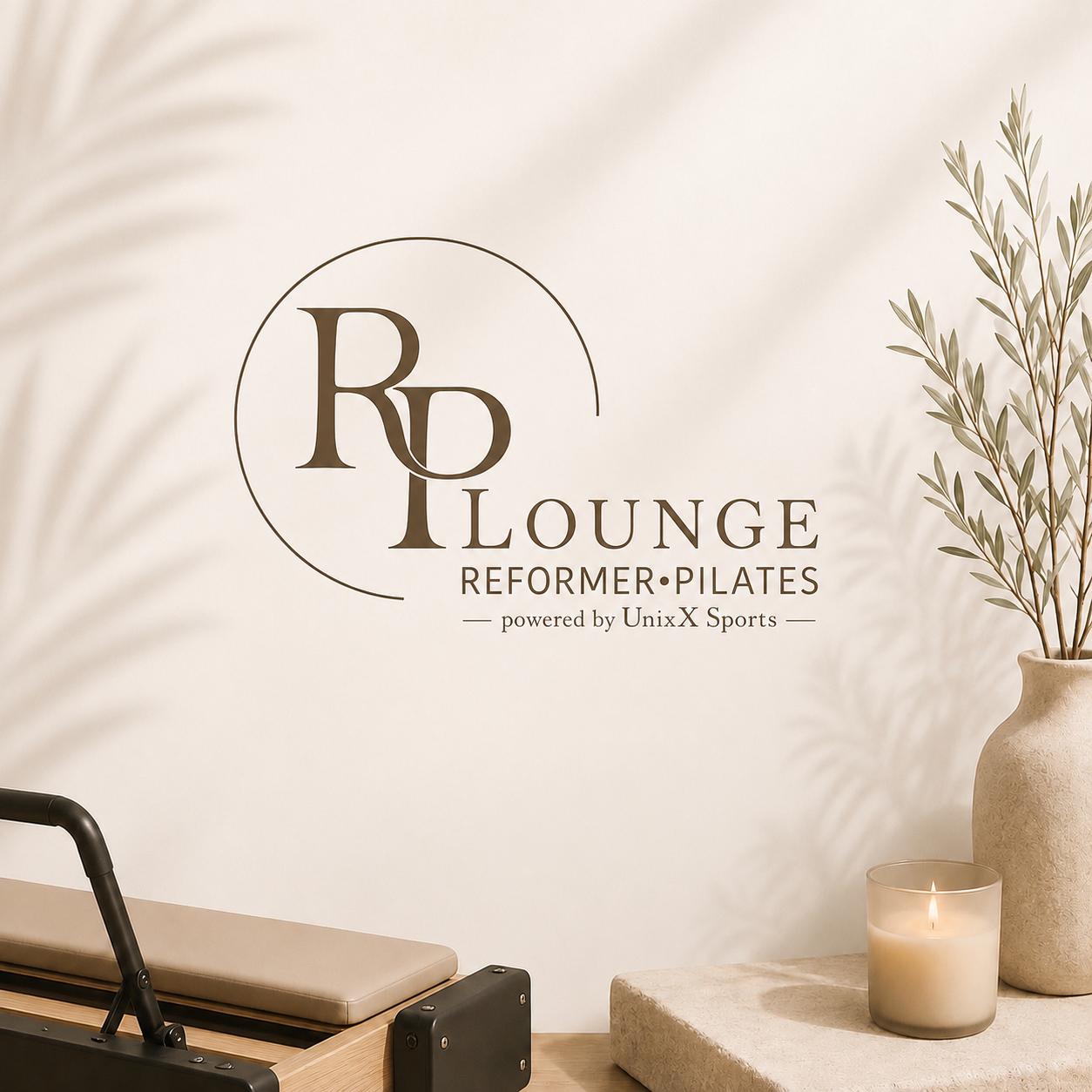 Schriftzug der Reformer Pilates Lounge an der Studiowand, davor ein Reformer